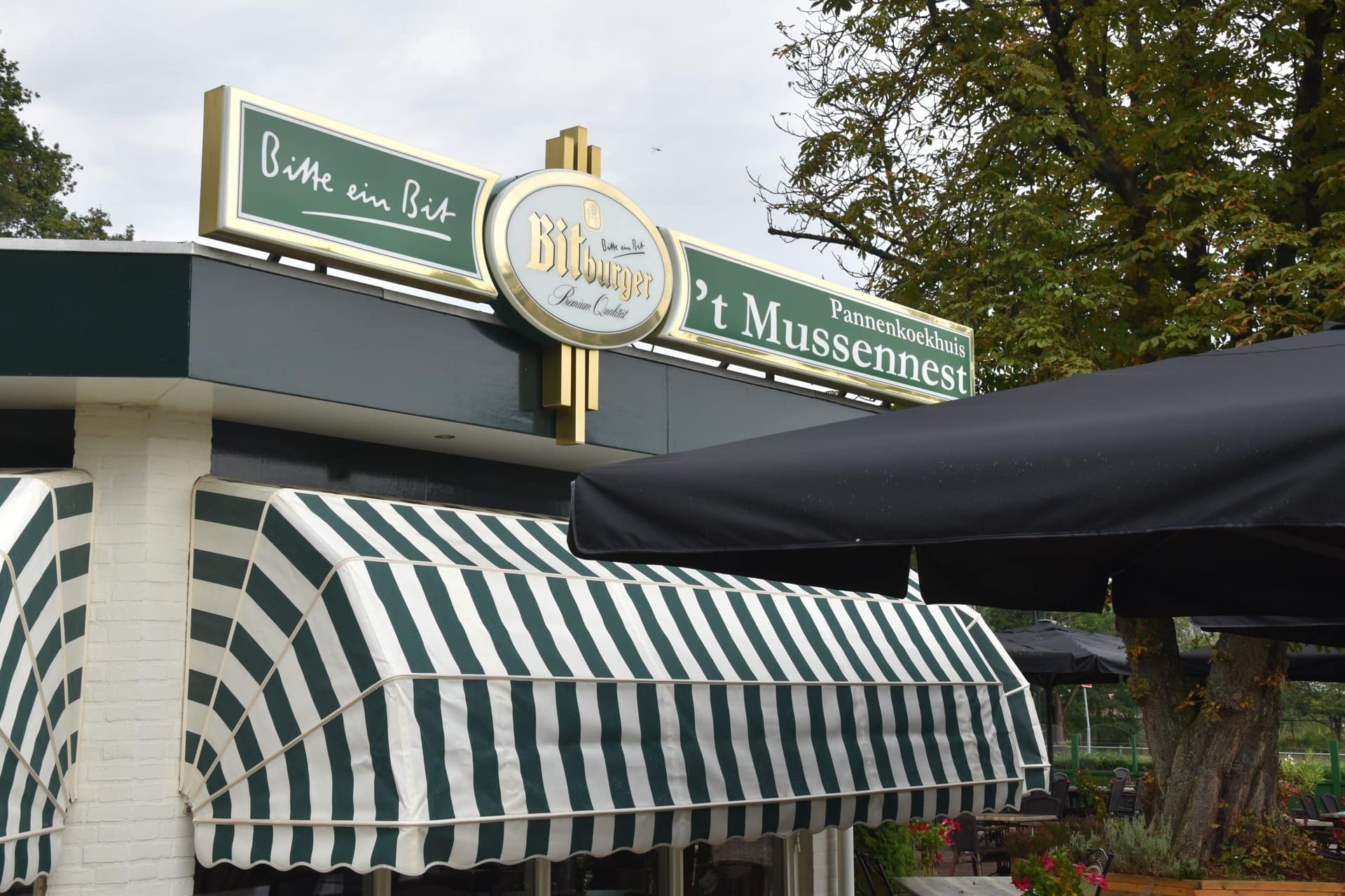 De gevel van Pannenkoekhuis 't Mussennest met het bord boven de groen met witte luifel.