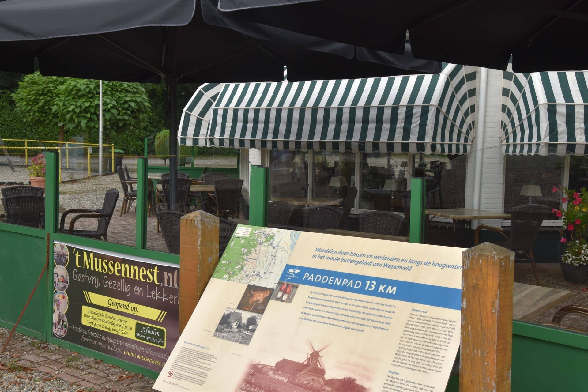 Het informatiebord van het paddenpad bij de ingang van 't Mussennest, naast het terras met de gestreepte luifel.