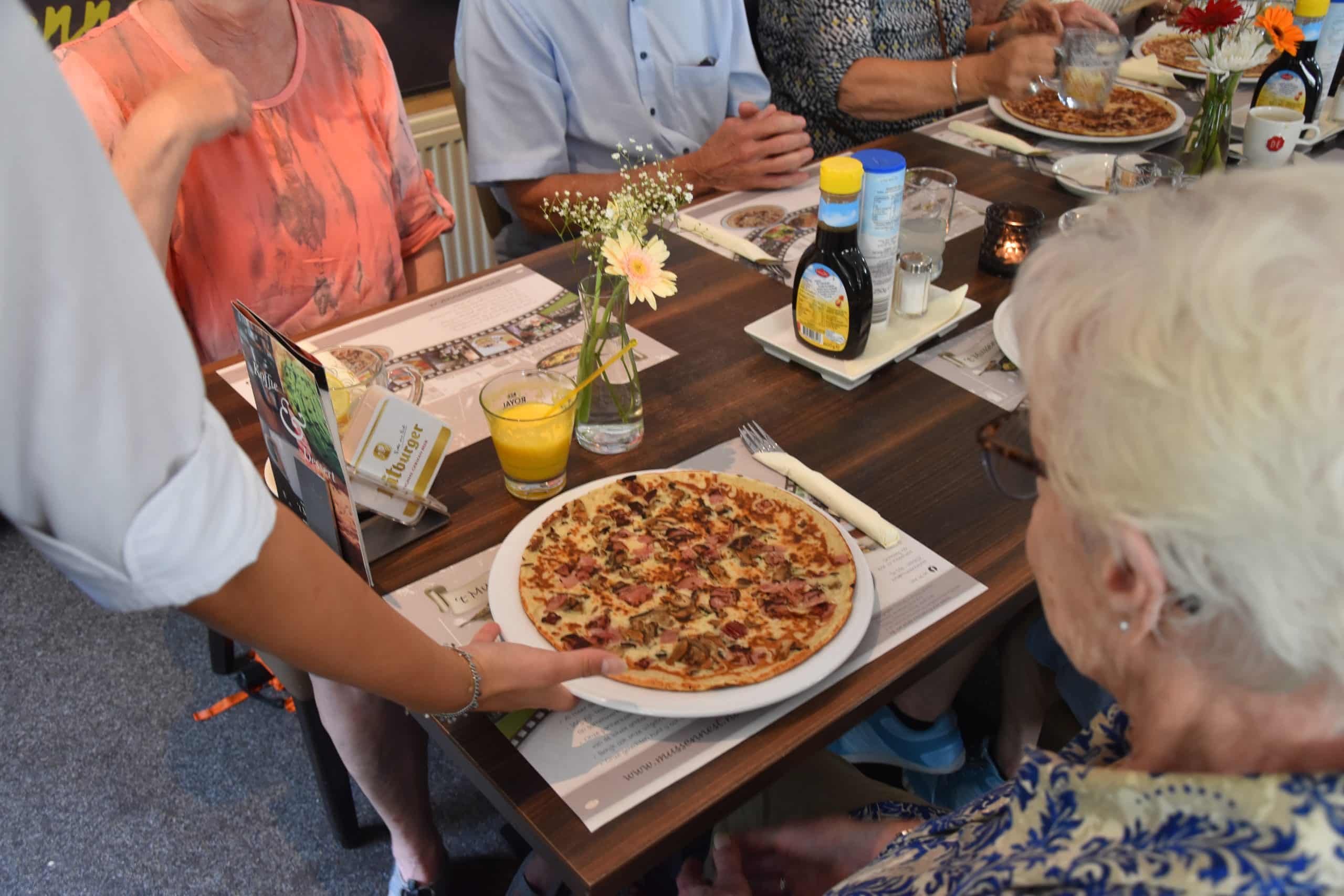 Een hartige pannenkoek met ham en champignons wordt aan tafel geserveerd.
